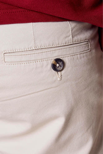 Bermuda beige de Bruce & Butler, avec une poche à boutons et une texture lisse et uniforme.