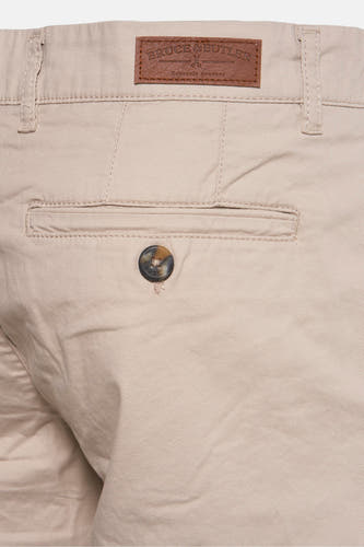 Bermuda beige de Bruce & Butler, avec un nœud brun sur la poche arrière et le logo de marque sur la ceinture.