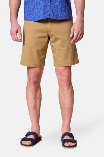 Shorts bruns de Bruce & Butler, avec un design simple et portés avec une chemise bleue et des sandales.