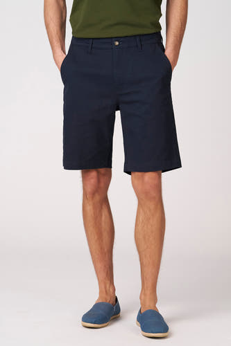 Blauwe bermuda van Bruce & Butler, met steekzakken en gedragen met blauwe espadrilles.
