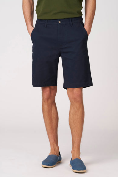 Bermuda bleu de Bruce & Butler, avec poches latérales et porté avec des espadrilles bleues.