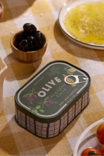 Groene soja-kaars in blik van PADDY WAX met olijfbladprint, op geruit tafelkleed, lifestyle shot