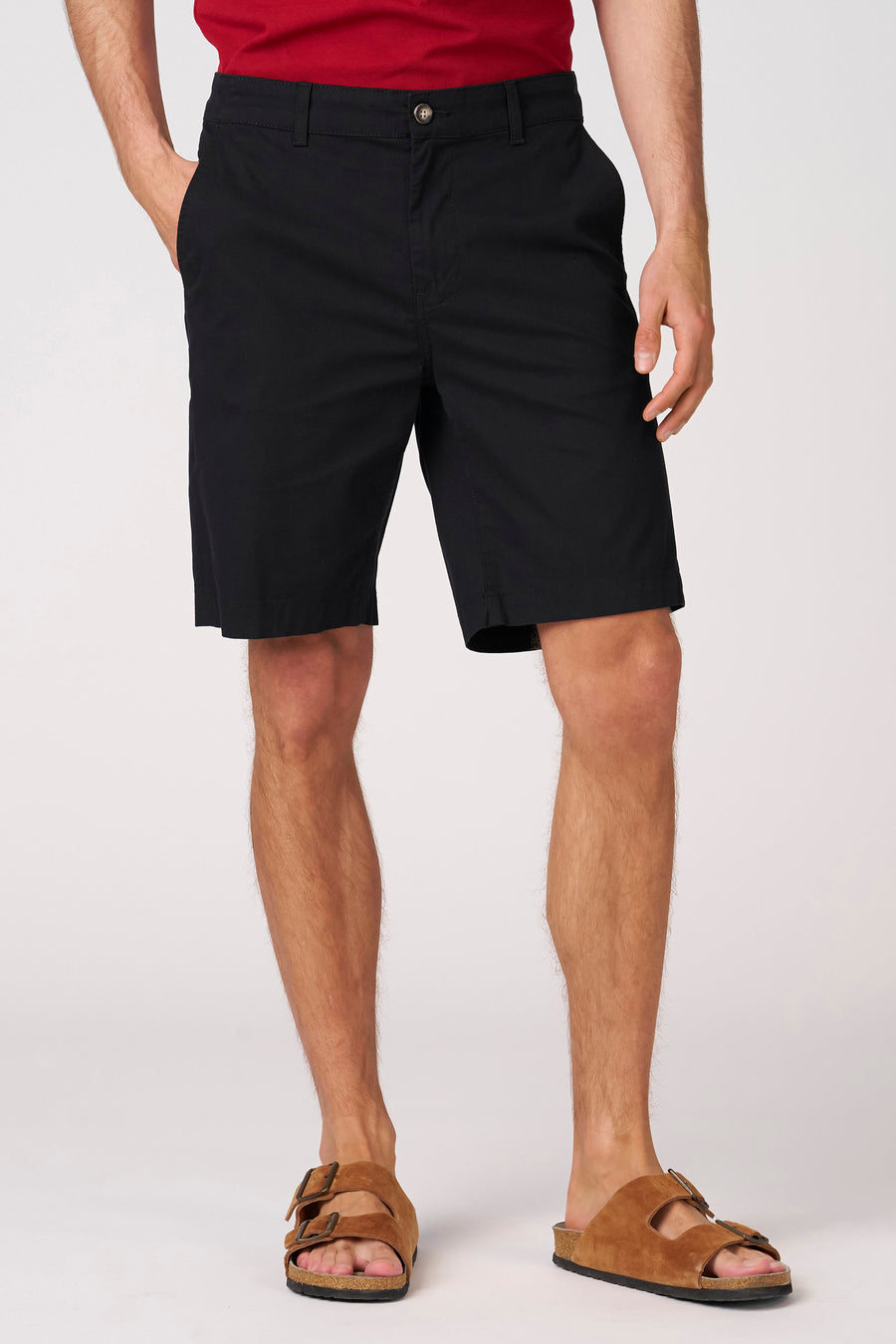 Short bermuda noir de Bruce & Butler, porté avec des sandales marron et un t-shirt rouge.