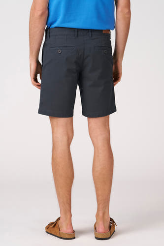 Blauwe short van Bruce & Butler, gezien van achteren, met zakken en een bruin leren detail, gedragen met sandalen.
