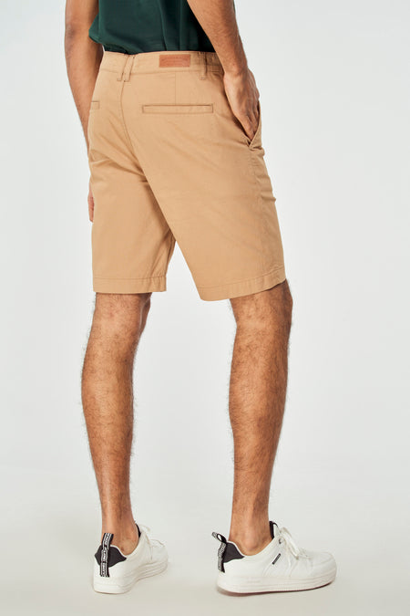 Short brun de Bruce & Butler, vu de l'arrière, avec une poche latérale et des baskets blanches.