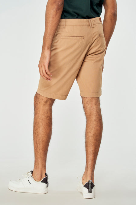 Short brun de Bruce & Butler, vu de de'arrière, combiné avec un t-shirt vert foncé et des baskets blanches.