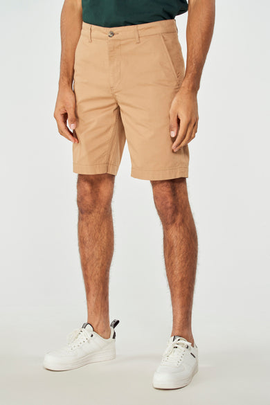Short brun de Bruce & Butler, avec un dessin lisse, porté avec un t-shirt vert et des baskets blanches.