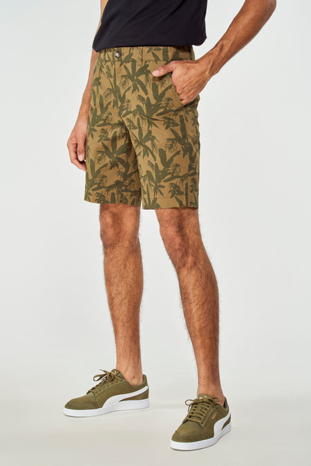 Groene short van Bruce & Butler, met palmboomprint, gedragen met groene sneakers en een zwart T-shirt, zij aanzicht.
