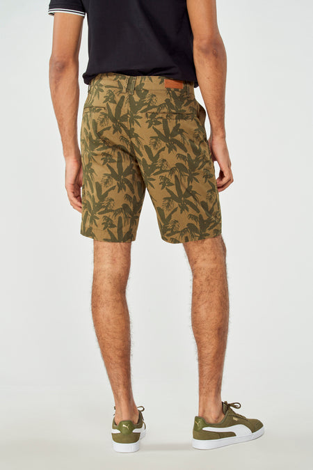 Short vert avec motif de palmier de Bruce & Butler, vu de dos, associé à des baskets vertes et un T-shirt noir.