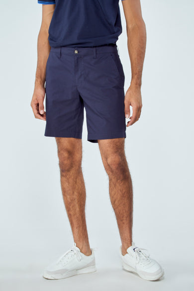 Short bermuda bleu de Bruce & Butler, vue de face, avec poches et baskets blanches.