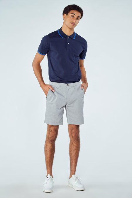 Short bleu de Bruce & Butler, associé à une polo marine avec des accents bleus et des sneakers blanches.