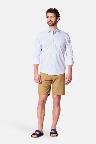 Chemise blanche à manches longues de Bruce & Butler, portée avec des shorts kaki et des sandales bleues.