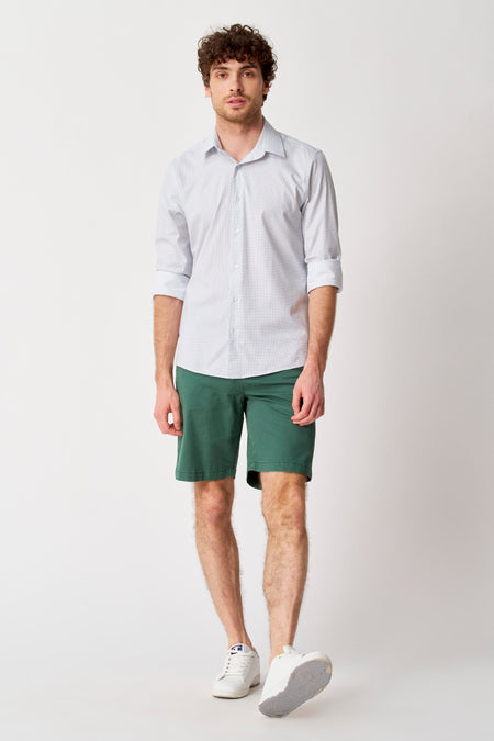 Chemise blanche à manches longues avec motif à pois subtil de Bruce & Butler, manches retroussées, portée avec un short vert foncé.