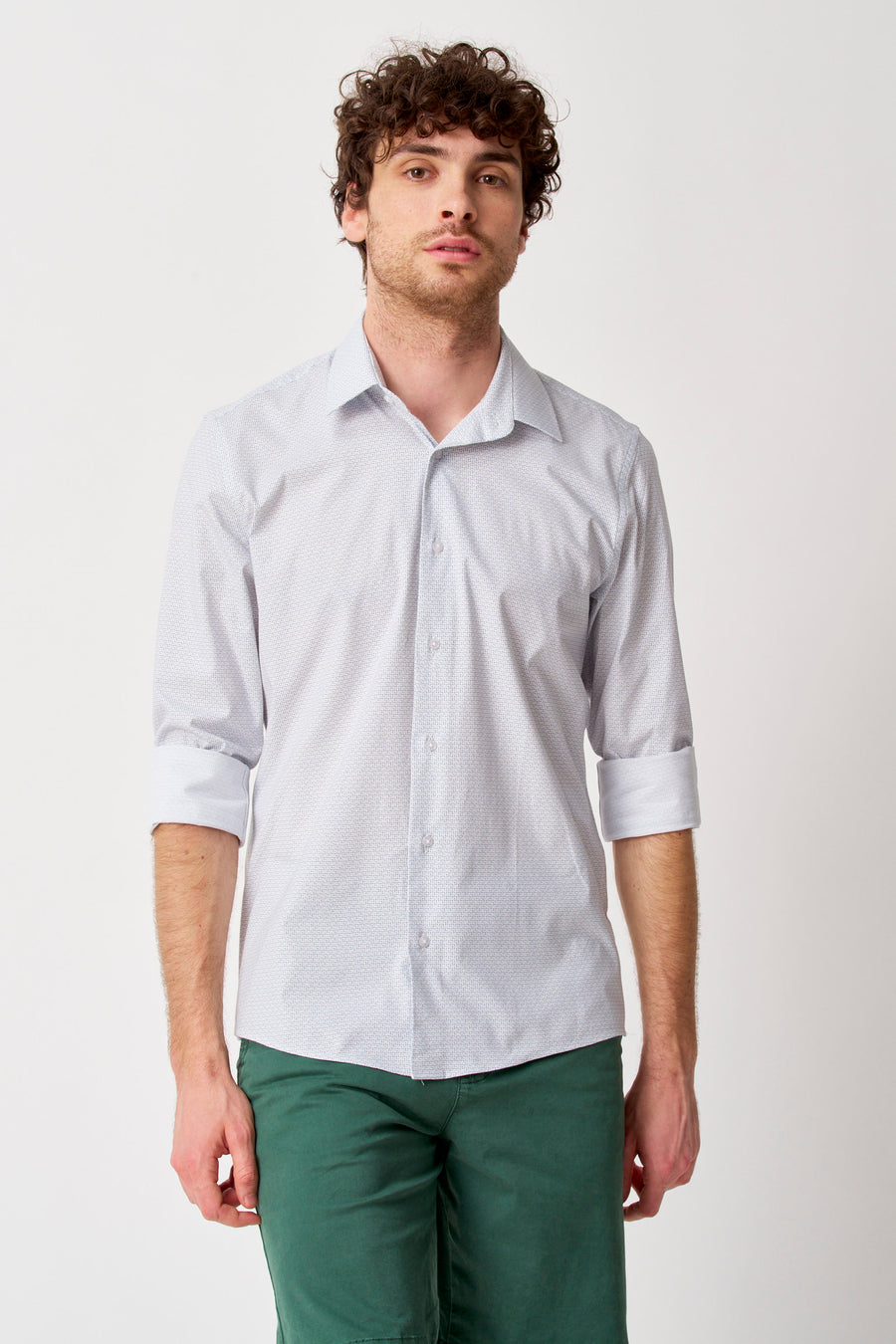 Chemise blanche à manches longues de Bruce & Butler, avec motif subtil, manches retroussées et portée avec un pantalon vert.