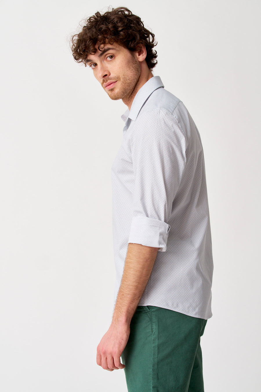 Chemise blanche à manches longues de Bruce & Butler avec motif à petits pois, manches retroussées, portée avec un pantalon vert, vue de côté.