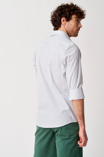 Chemise blanche à manches longues de Bruce & Butler, vue de côté, à motif à pois, manches retroussées et short vert.