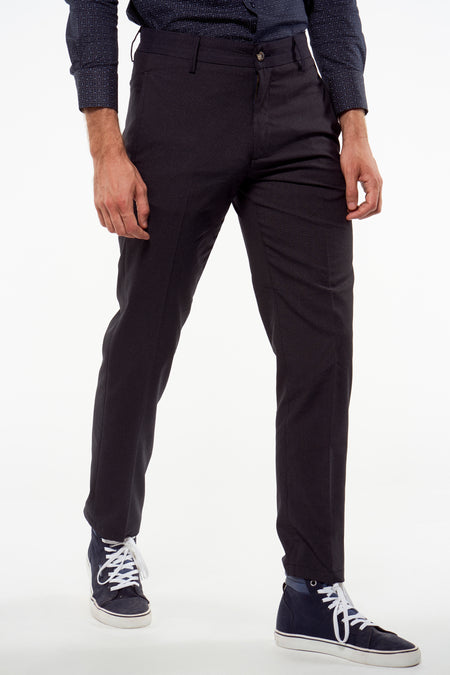 Pantalon de costume bleu foncé de Bruce & Butler avec motif à carreaux subtil, fermeture à boutons, porté avec une chemise à pois et des baskets.