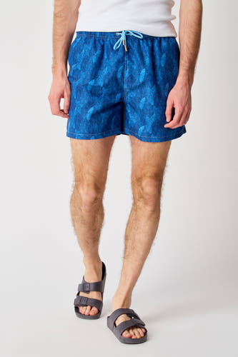 Maillot de bain bleu de Bruce & Butler, avec un motif végétal et porté avec des sandales grises.