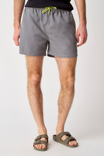 Pantalon gris Bruce & Butler, avec des cordons verts et porté avec des sandales vert olive.
