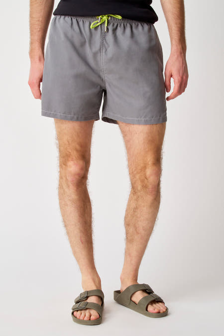 Pantalon gris Bruce & Butler, avec des cordons verts et porté avec des sandales vert olive.