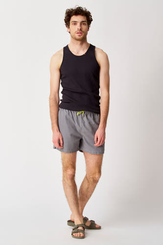 Pantalon gris Bruce & Butler, porté avec une chemise noire et des sandales.