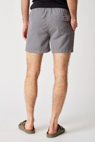 Pantalon gris Bruce & Butler, vu de l'arrière, avec une poche et porté avec des sandales.
