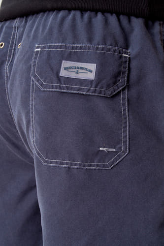 Blauwe zwembroek van Bruce & Butler, met witte stiksels en een achterzak met logo.