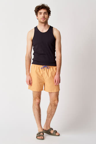 Pantalon de bain Bruce & Butler, avec une ceinture bleue, porté avec un chemisier noir et des sandales.