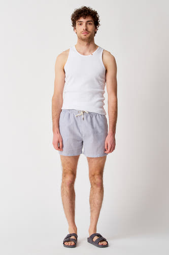 Pantalon de bain à rayures bleues de Bruce & Butler, porté avec un chemisier blanc et des sandales.
