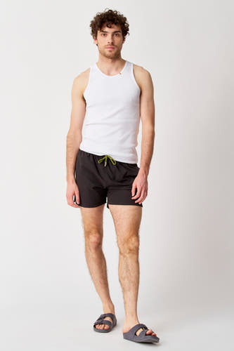 Chaussures noires Bruce & Butler, portées avec un t-shirt blanc et des sandales grises.