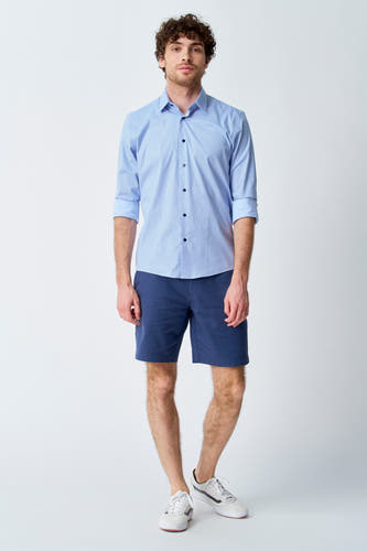 Short bleu de Bruce & Butler, associé à une chemise bleu clair et des baskets blanches.