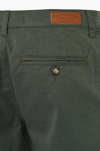 Short vert de Bruce & Butler, avec un détail de poche à bouton et une étiquette en cuir brun de la marque.