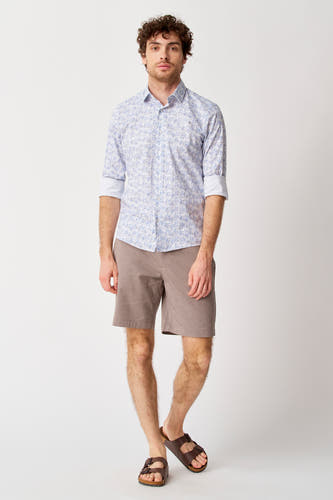 Short beige de Bruce & Butler, combiné avec un chemisier à fleurs bleu et blanc et des sandales brunes.