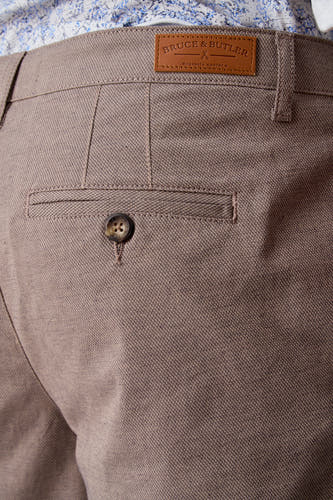 Short beige de Bruce & Butler, avec une poche arrière à bouton et une texture tissée.