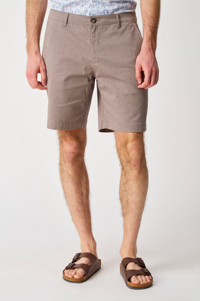 Man in taupe shorts en bruine sandalen.