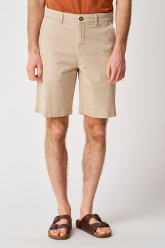 Short beige de Bruce & Butler, porté avec des sandales brunes et un t-shirt orange, cropped.