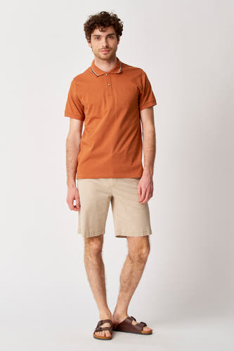 Beige court de Bruce & Butler, associé à un poloshirt orange et des sandales brunes.