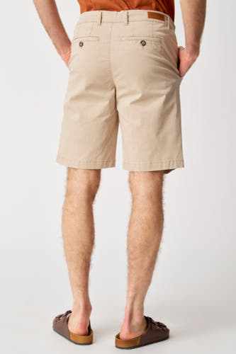 Short beige de Bruce & Butler, avec des poches arrière et porté avec des sandales brunes.
