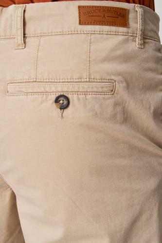 Short beige de Bruce & Butler, avec un nœud brun sur la poche arrière et une étiquette en cuir à la ceinture.