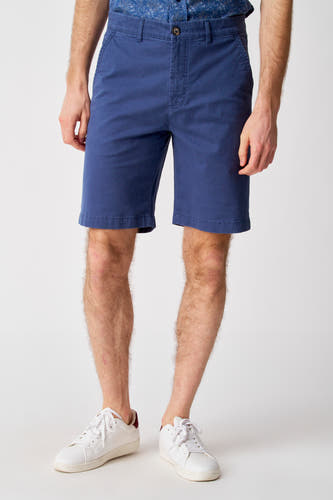 Short bleu de Bruce & Butler, porté avec un chemisier imprimé et des baskets blanches.