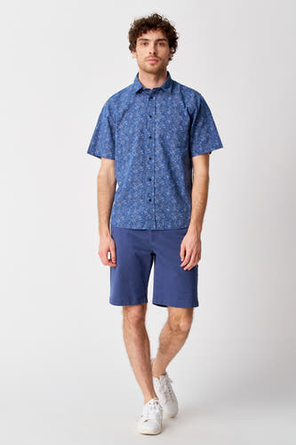 Short bleu de Bruce & Butler, associé à une chemise bleue imprimée et des baskets blanches.