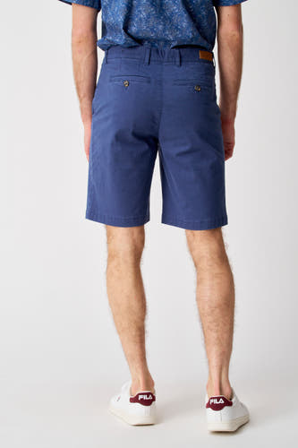 Short bleu de Bruce & Butler, vu de derrièrear avec des poches visibles et porté avec des baskets blanches.