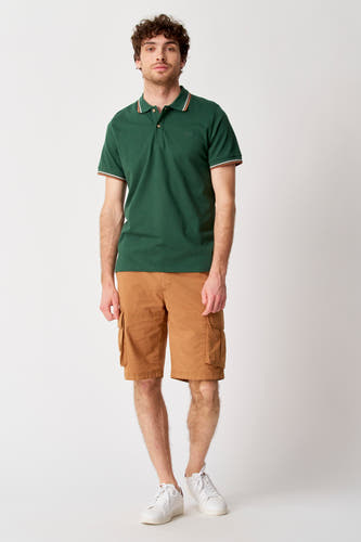 Short brun de Bruce & Butler, avec poches sur les côtés, associé à une polo verte et des baskets blanches.
