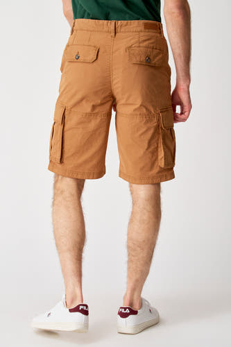 Short brune de Bruce & Butler, avec des poches cargo et deux poches arrière, portée avec des baskets blanches.