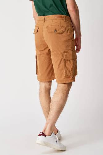 Pantalon court brun de Bruce & Butler, avec des poches cargo et porté avec un t-shirt vert et des baskets blanches.