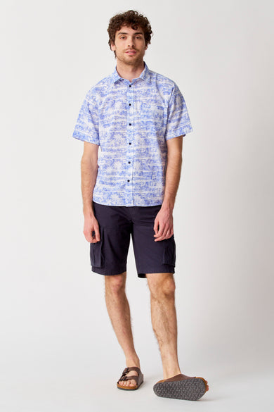 Bleu court de Bruce & Butler, associé à une chemise bleue et blanche et des sandales brunes.