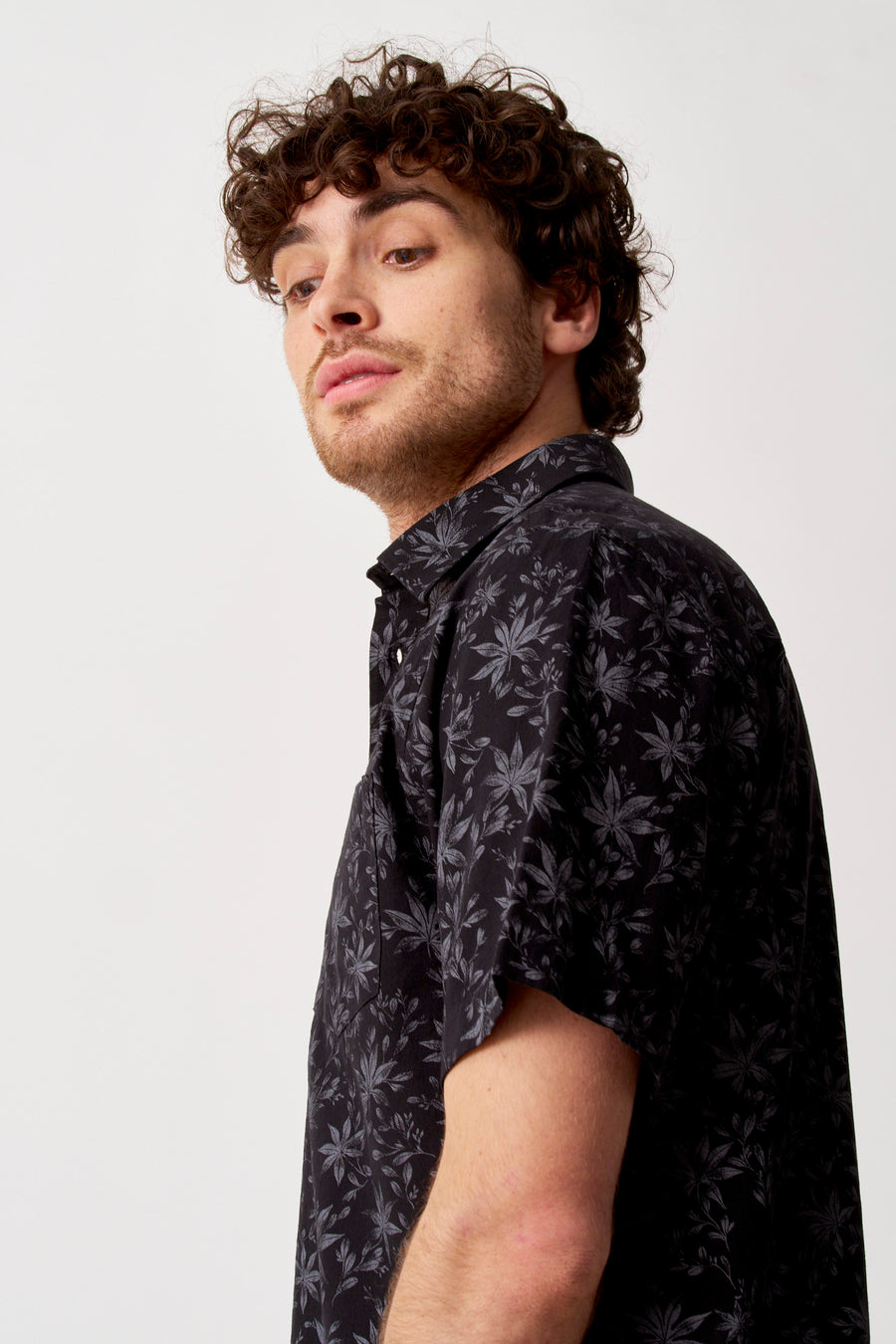Chemise noire à manches courtes de Bruce & Butler avec motif de feuilles gris foncé, portée par un homme.