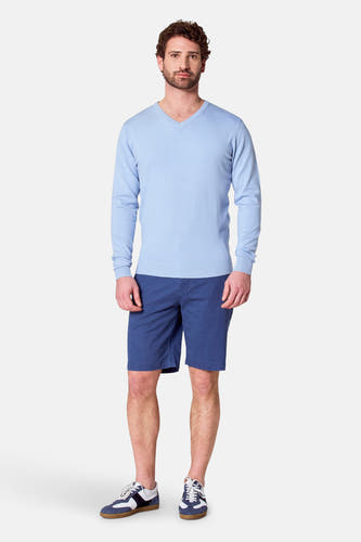 T-shirt bleu clair avec col V de Bruce & Butler, porté avec des short bleus et des baskets.