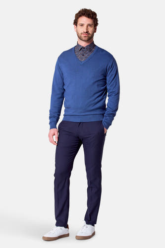Pull à col V bleu de Bruce & Butler, associé à une chemise imprimée et un pantalon bleu marine.