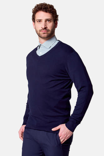 T-shirt à col V bleu de Bruce & Butler, avec un chemisier rayé bleu clair en dessous, debout.